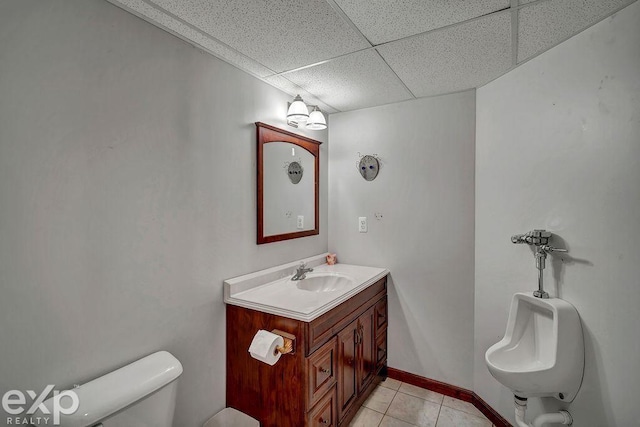 bathroom with tile patterned flooring, sink, a paneled ceiling, and toilet