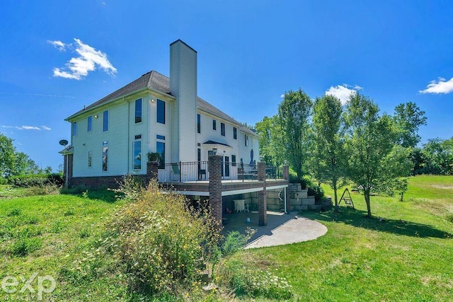 back of property with a wooden deck, a patio area, and a lawn