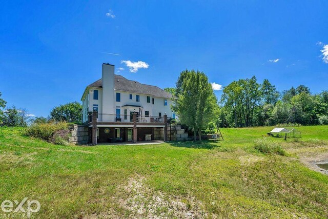 back of property with a lawn and a deck