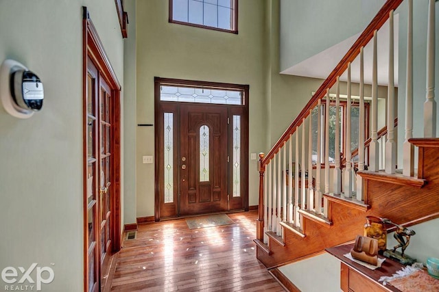 foyer with a towering ceiling, hardwood / wood-style flooring, and a healthy amount of sunlight