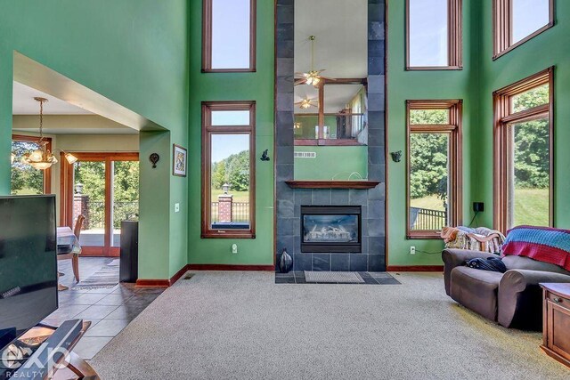 carpeted living room featuring a notable chandelier, a tile fireplace, and a high ceiling