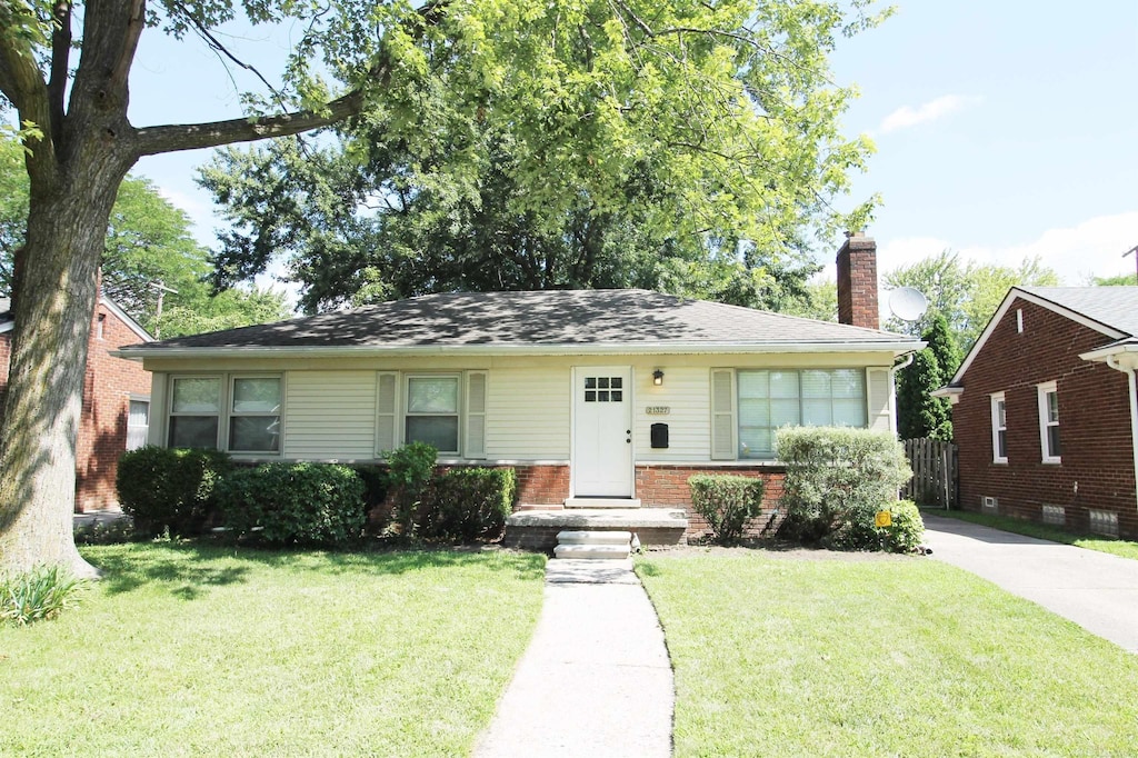 view of front of home featuring a front yard, brick siding, fence, and a chimney