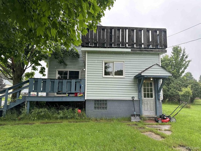 back of property featuring a deck and a yard