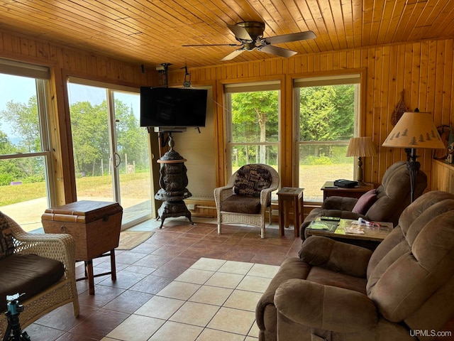 tiled living room featuring ceiling fan, wooden walls, and wooden ceiling