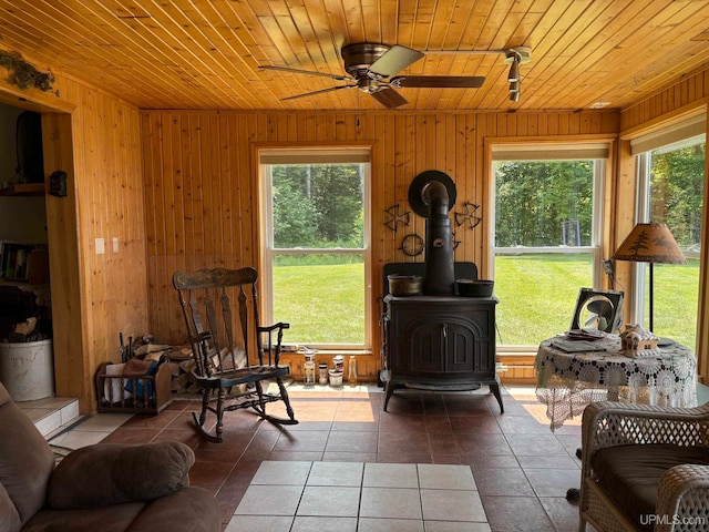 sunroom with ceiling fan, wood ceiling, and a wood stove