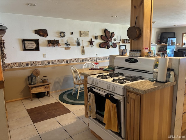 14998 N Superior Rd, Houghton, MI 49931 - kitchen featuring white range with gas cooktop, light tile patterned flooring, brown cabinets, and open floor plan