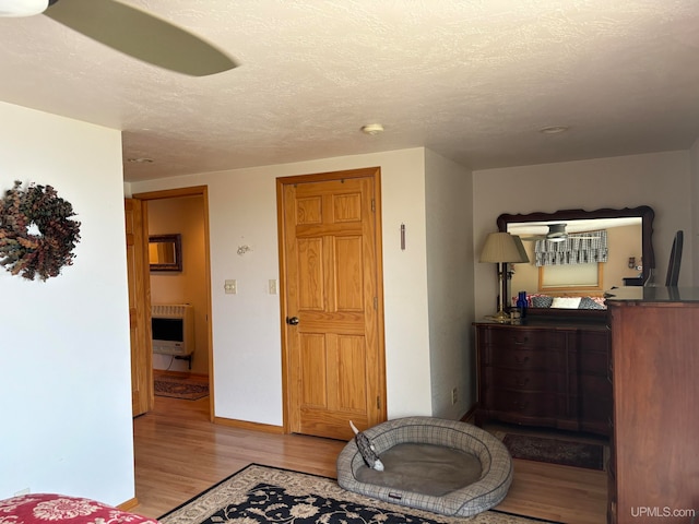 bedroom featuring a textured ceiling, light hardwood / wood-style floors, and radiator