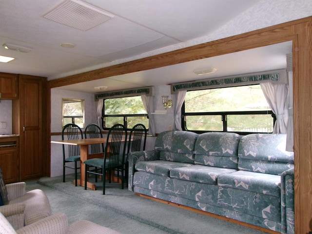 living room with visible vents, beamed ceiling, and carpet flooring