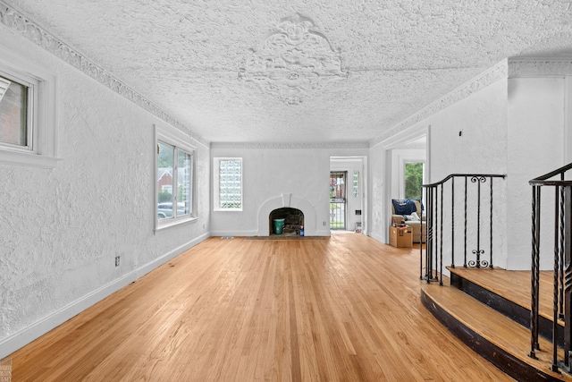 unfurnished living room with a textured ceiling, plenty of natural light, and light hardwood / wood-style floors