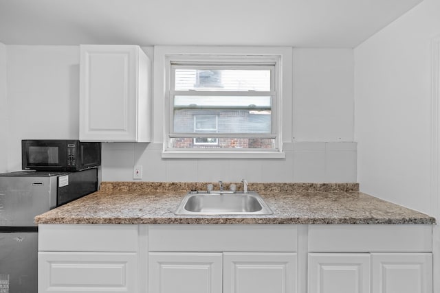 kitchen with sink, backsplash, white cabinetry, and light stone counters