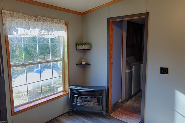 interior space featuring a wood stove, ornamental molding, wood-type flooring, and washer and dryer