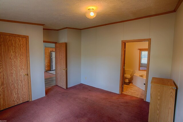 unfurnished bedroom featuring carpet, ensuite bathroom, a textured ceiling, and crown molding