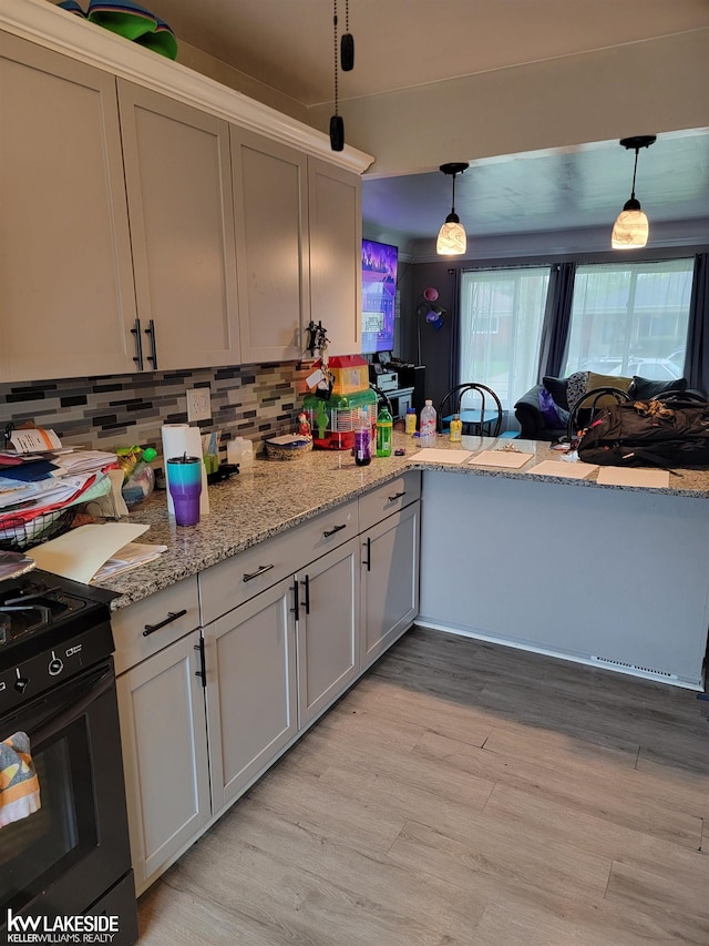 kitchen with black range with electric stovetop, light hardwood / wood-style flooring, light stone counters, tasteful backsplash, and pendant lighting