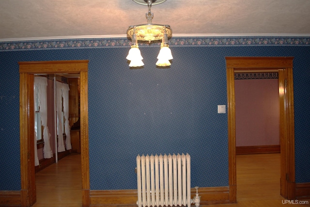 dining area featuring radiator heating unit, baseboards, a chandelier, and wood finished floors