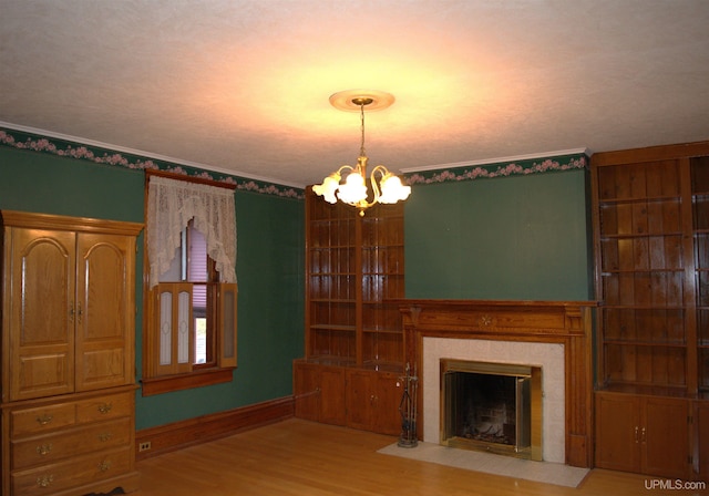 unfurnished living room featuring a tiled fireplace, baseboards, a notable chandelier, and wood finished floors