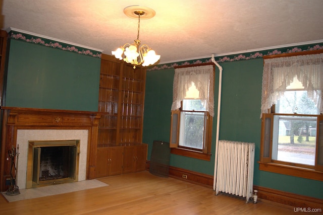 unfurnished living room with radiator, an inviting chandelier, and plenty of natural light