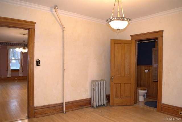 interior space with crown molding, radiator, a chandelier, wood finished floors, and baseboards