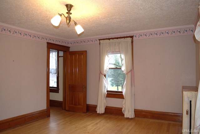 interior space featuring light wood-type flooring, baseboards, plenty of natural light, and a textured ceiling