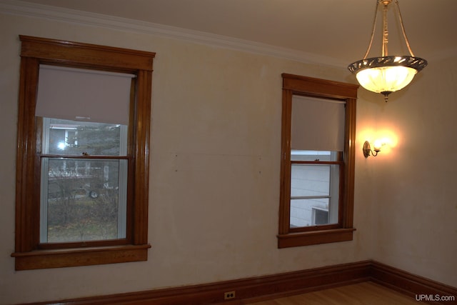 unfurnished room featuring baseboards, crown molding, and wood finished floors