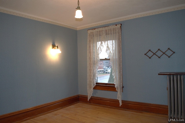 unfurnished room featuring baseboards, light wood-type flooring, crown molding, and radiator heating unit