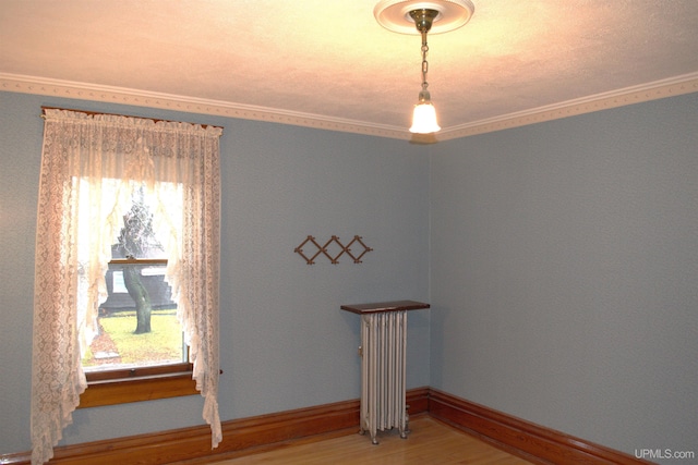 spare room featuring crown molding, radiator heating unit, and wood finished floors