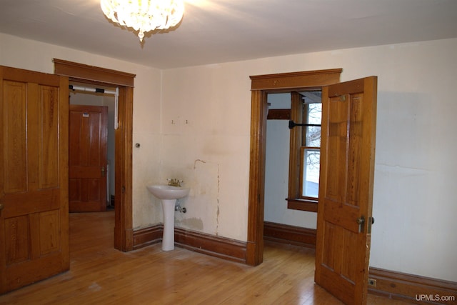 unfurnished room with a sink, light wood finished floors, and a chandelier