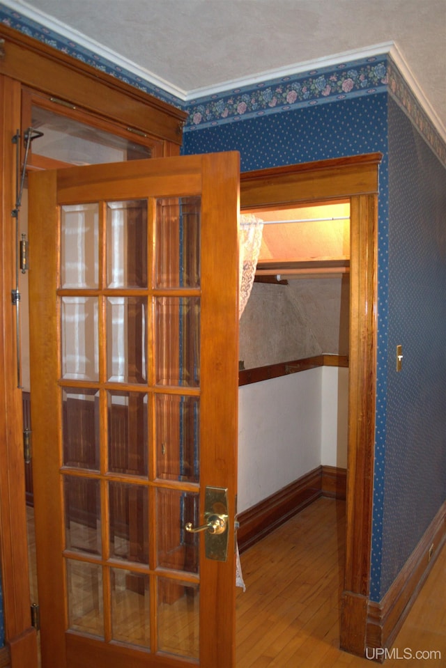 hall featuring baseboards, wood finished floors, and wallpapered walls