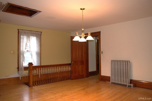 unfurnished room featuring a notable chandelier, visible vents, radiator, and wood finished floors