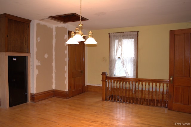 unfurnished room with a chandelier, wood finished floors, and baseboards
