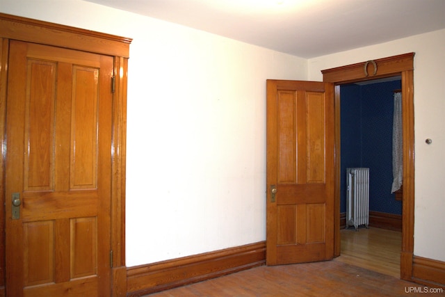 empty room featuring baseboards, radiator, and wood finished floors