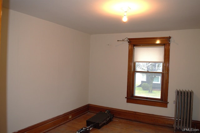 spare room with wood finished floors, radiator heating unit, and baseboards