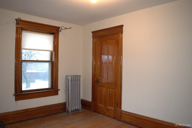 unfurnished room with wood finished floors and radiator heating unit