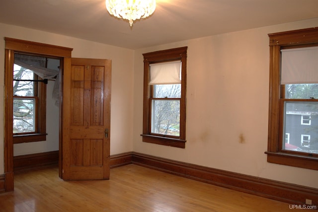 unfurnished bedroom with an inviting chandelier, light wood-type flooring, and baseboards