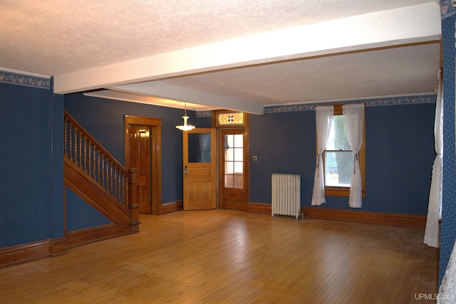 foyer entrance featuring baseboards, beamed ceiling, wood finished floors, stairs, and radiator heating unit