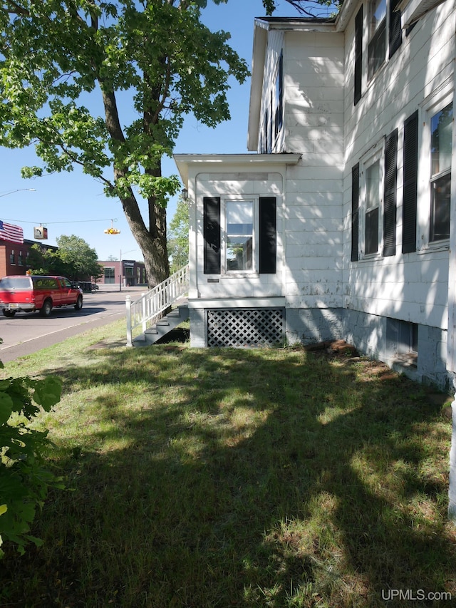 view of home's exterior with entry steps and a lawn