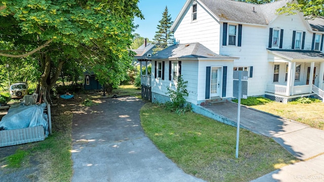 view of front of house featuring aphalt driveway, a front yard, and a shingled roof