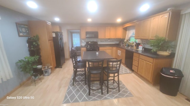 kitchen featuring a breakfast bar, decorative backsplash, light hardwood / wood-style floors, a kitchen island, and fridge