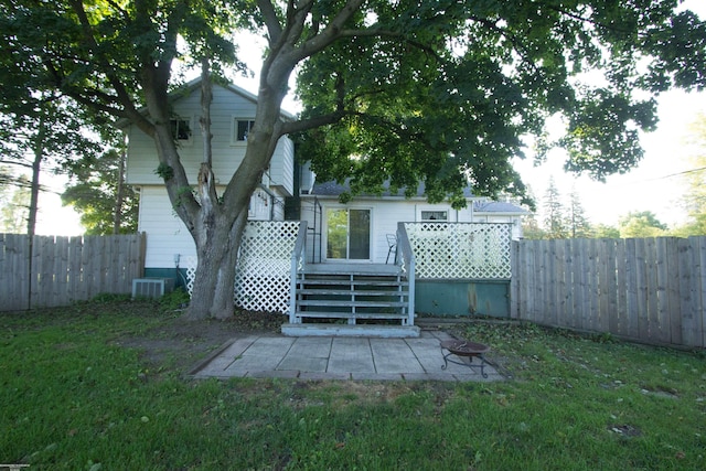 back of house featuring an outdoor fire pit, central AC unit, a deck, and a lawn