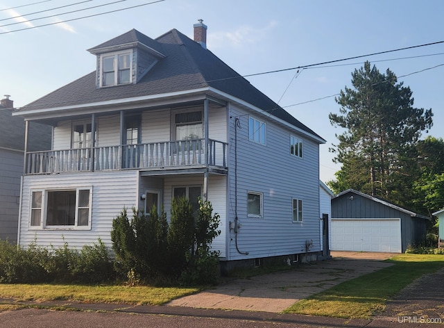 view of front facade featuring a balcony, a garage, and an outbuilding