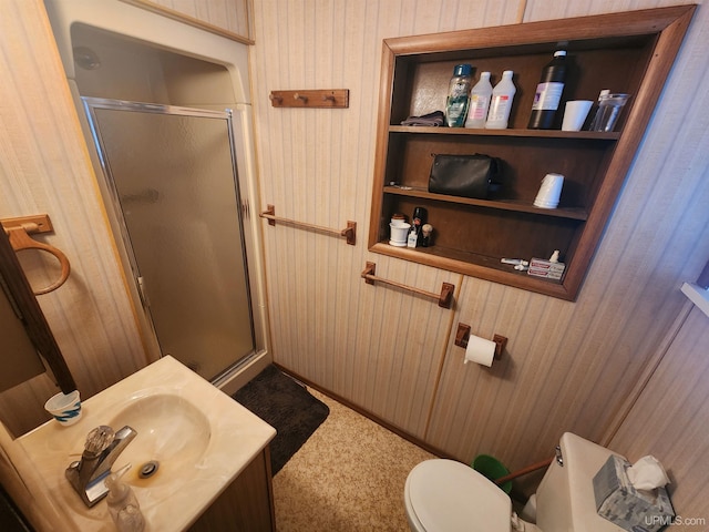 bathroom with wooden walls, a shower with door, vanity, and toilet