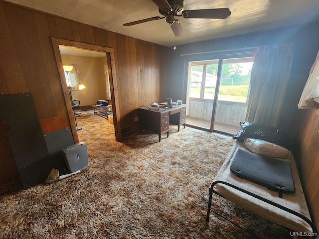 interior space with ceiling fan and wooden walls