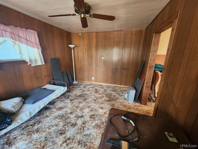 interior space with ceiling fan and wooden walls