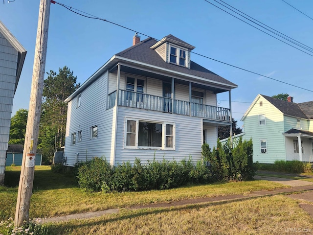 view of front property featuring a balcony and a front yard