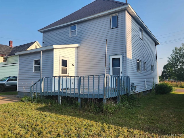 rear view of house with a deck and a lawn