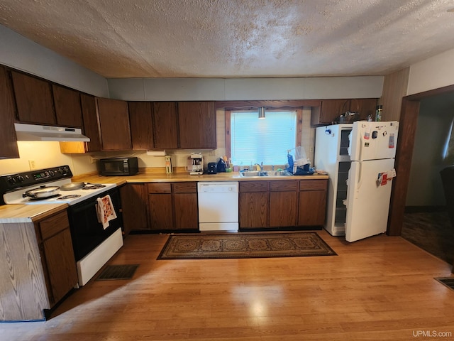 kitchen featuring a textured ceiling, white appliances, sink, and light hardwood / wood-style flooring