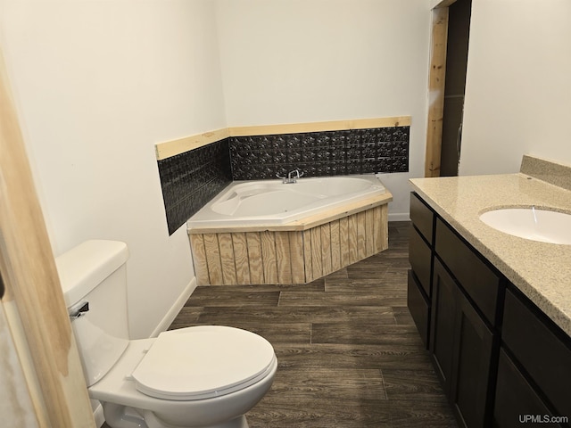 bathroom featuring a bath, vanity, toilet, and wood finished floors