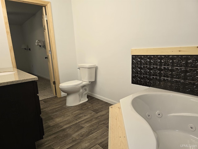 full bathroom featuring toilet, wood finished floors, vanity, baseboards, and a tub with jets