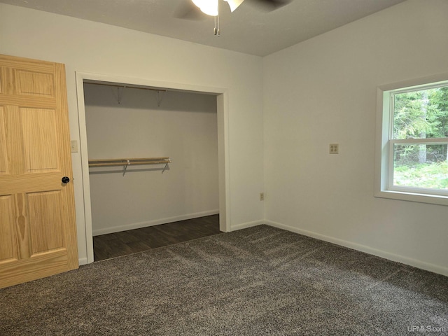 unfurnished bedroom with ceiling fan, a closet, dark carpet, and baseboards