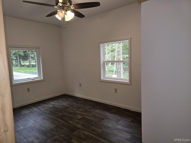 empty room featuring a ceiling fan, baseboards, and dark wood-type flooring