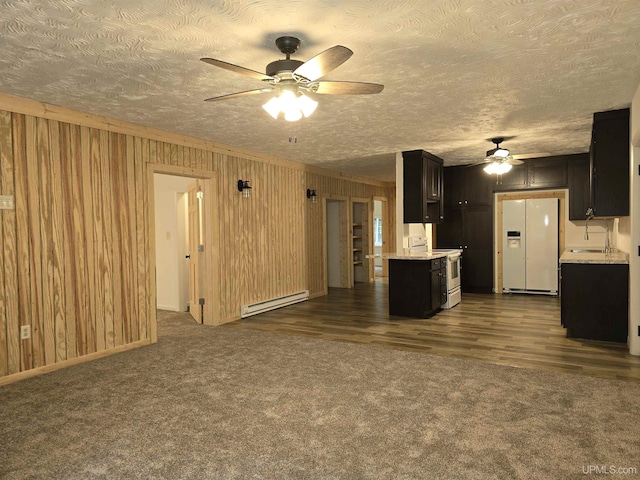 unfurnished living room featuring a baseboard radiator, wooden walls, dark carpet, and a textured ceiling